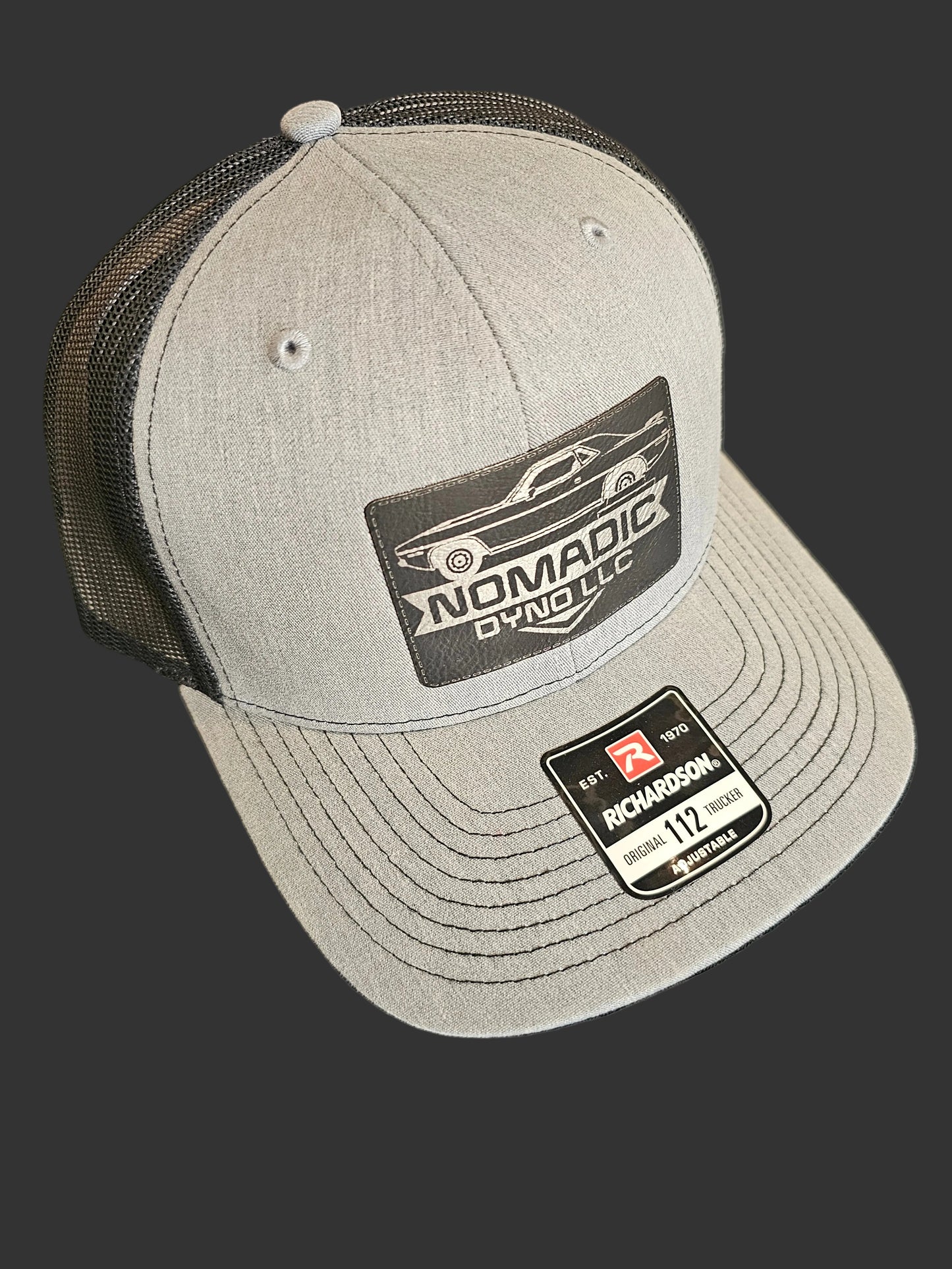 Gray cap with brand logos on a black background Nomadic Dyno