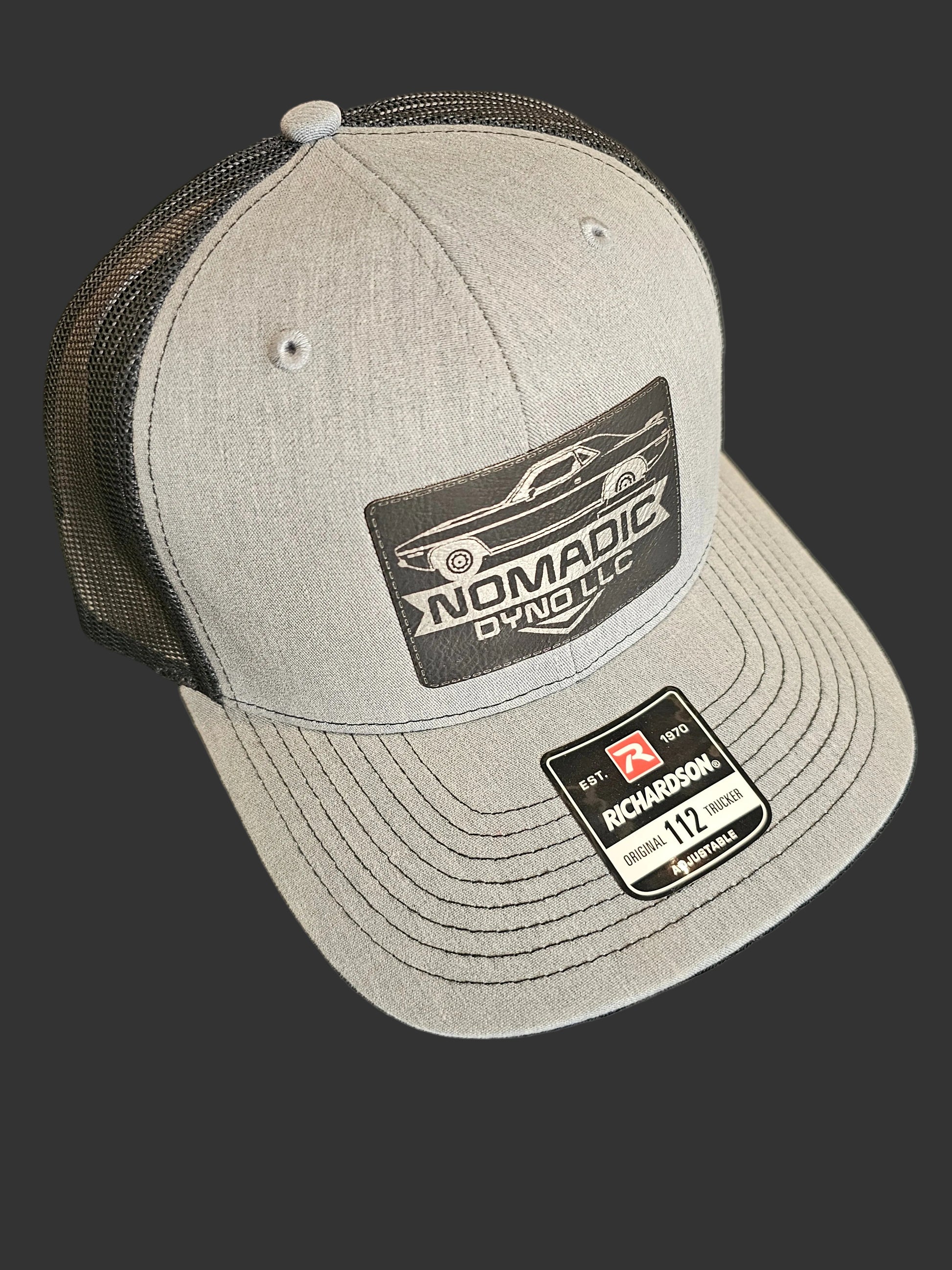 Gray cap with brand logos on a black background Nomadic Dyno