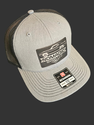 Gray cap with brand logos on a black background Nomadic Dyno